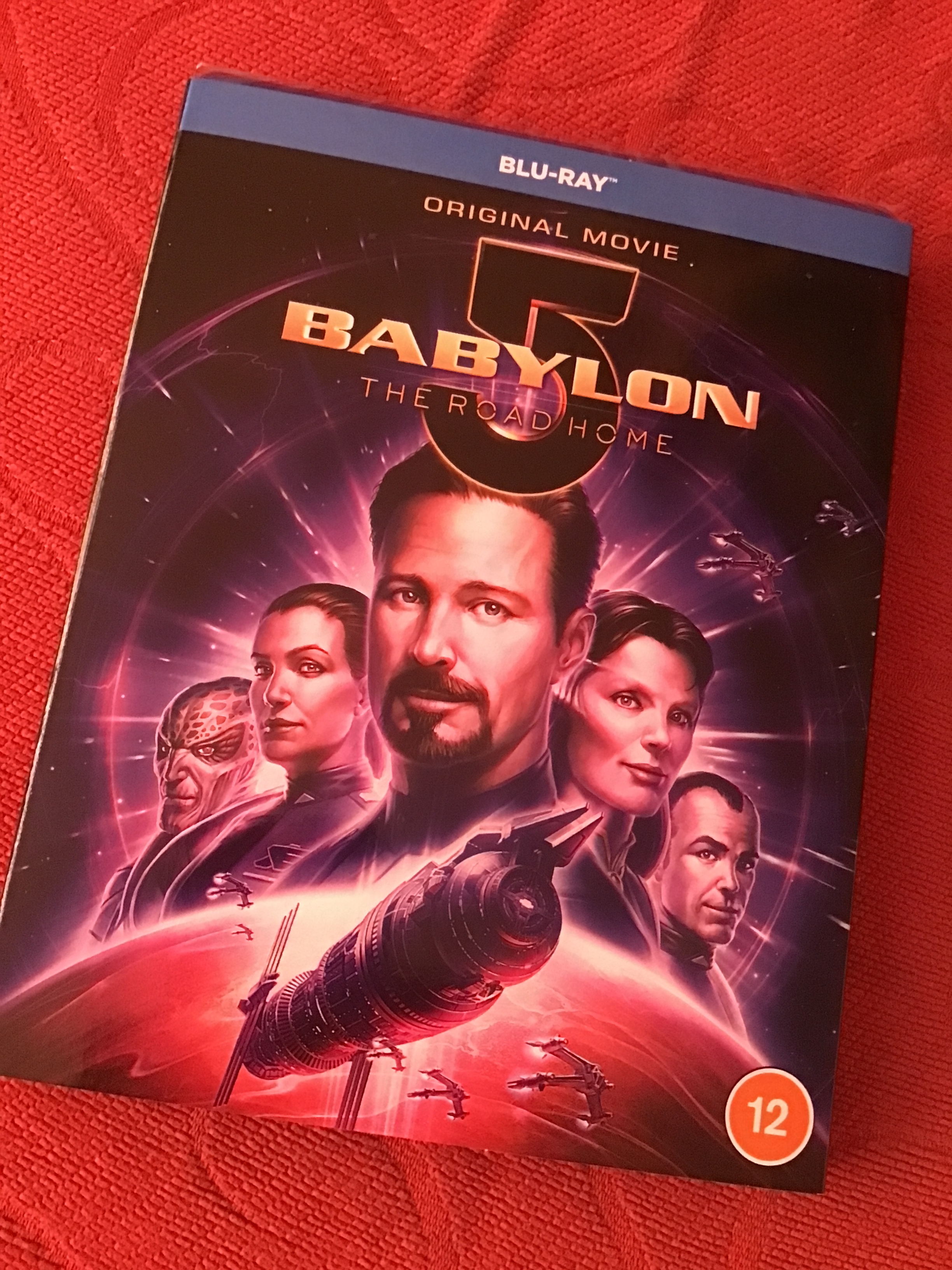 Photo of the Babylon 5 animated movie "The Road Home" Blu-ray version sitting on a red sofa