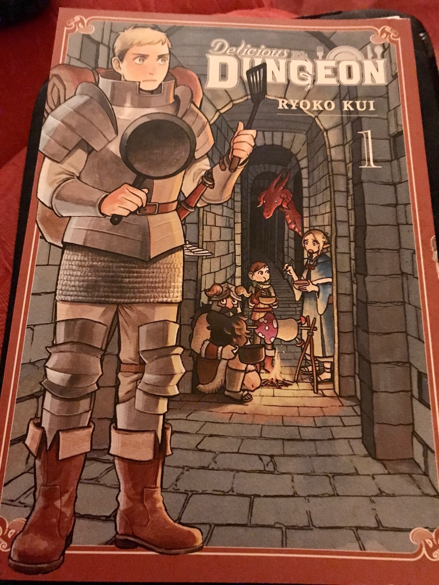 This shows a dungeoneer in armour at the fron holding a fry an pan and spatula. Behind him, deeper in the dungeon, are his fellow adventurers. And in the distance a red dragon watches.