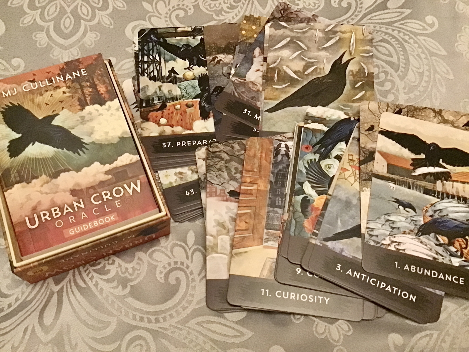 "Urban Crow" oracle cards, spread across a bedspread